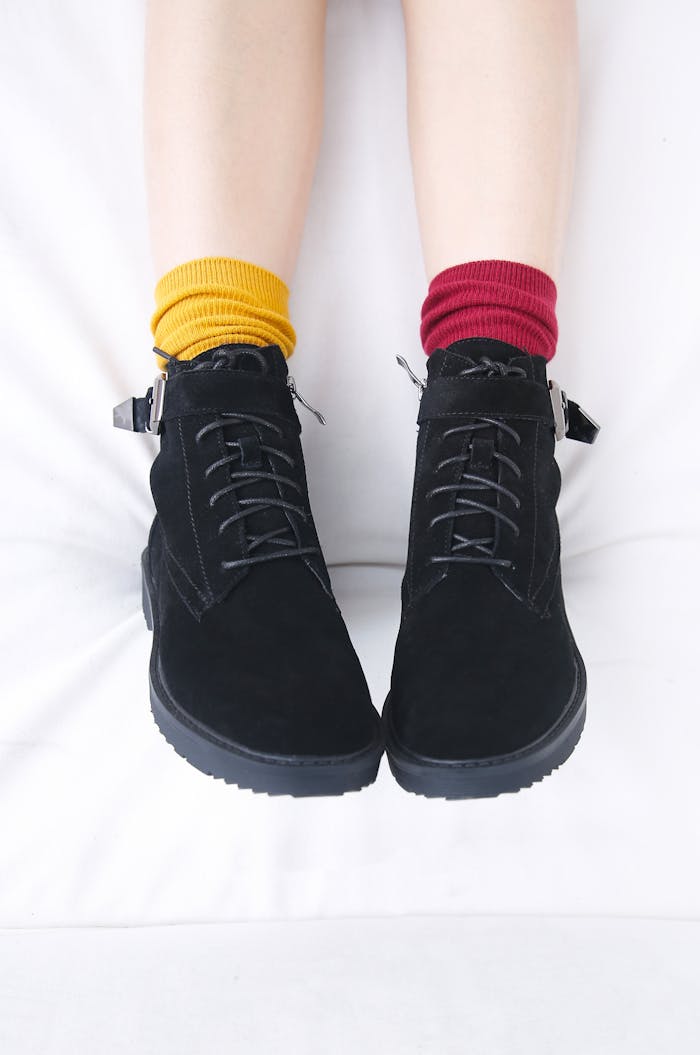 Stylish black boots paired with vibrant socks against a white background.